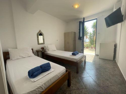 a room with two beds and a television in it at Mini Beach House in Logaras