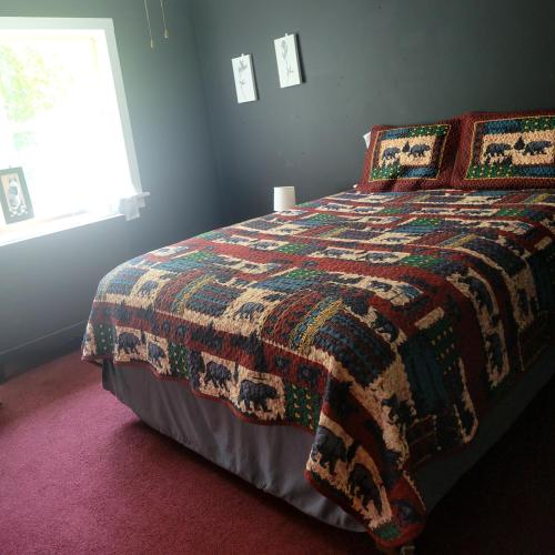 Pleasant Place II Victor Countryside في فيكتور: غرفة نوم مع سرير وبطانية ملونة