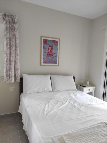 1 cama blanca en un dormitorio con una foto en la pared en GERAKOFOLIA-VILLA, en Nikiana