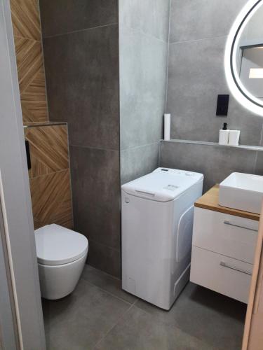 a bathroom with a toilet and a washer and dryer at Apartament Nowa letnica in Gdańsk