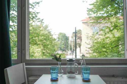 einen Tisch mit Gläsern und Flaschen am Fenster in der Unterkunft City Center Coziest Studio in Tampere