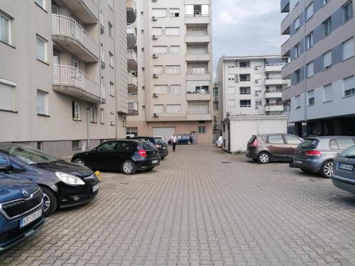 a parking lot with cars parked in front of buildings at Apartman Breza 3 in Kruševac