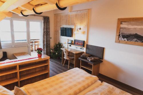 a bedroom with a bed and a desk and a table at Berghotel Sonnenklause in Sonthofen