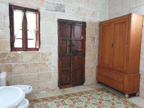 a bathroom with a toilet and a wooden cabinet at Tifkira (The Memory) in Birgu