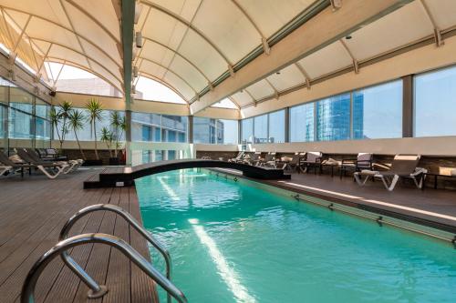 a swimming pool in a building with tables and chairs at Best Western Premier Marina Las Condes in Santiago