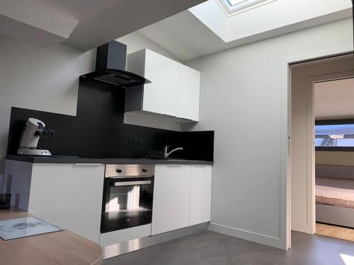 une cuisine avec des armoires blanches et un four à plaques de cuisson dans l'établissement Robert's Family Petite Maison de Ville, à Plancoët