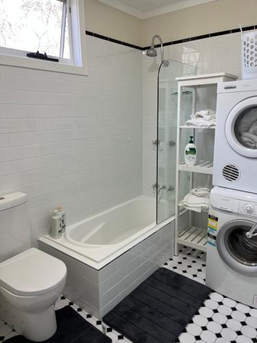 ein Badezimmer mit einer Badewanne, einem WC und einer Waschmaschine in der Unterkunft Blissful Mountain Stay in Katoomba