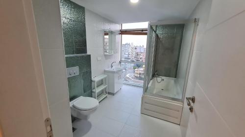 a bathroom with a toilet and a shower and a window at Kleopatra Carina Apart in Alanya