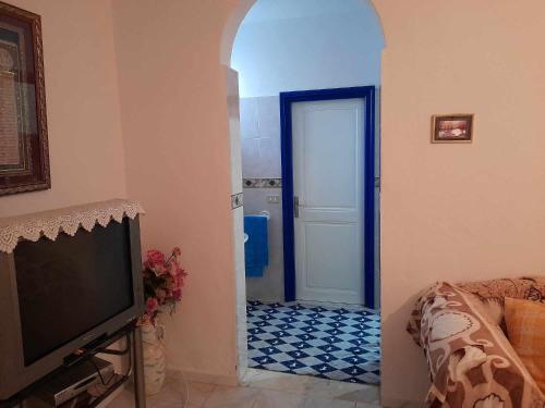 sala de estar con TV y puerta con suelo de baldosa. en Maison à Hergla, Sousse, Tunisie en Harqalah