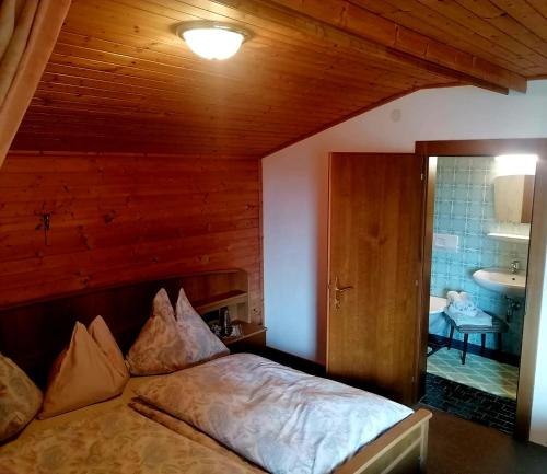 a bedroom with a bed and a bathroom with a sink at Kohlegghof in Schwemmberg