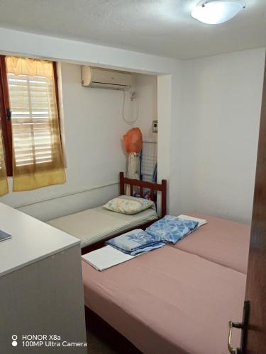 two beds in a small room with a window at Apartmani Gina in Sutomore