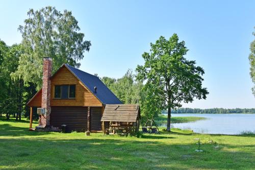 a log cabin on the shore of a lake at Duriu sodyba in Molėtai