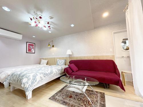 a bedroom with a bed and a red couch at Ocean Villa Tin Gala - Vacation STAY 98840v in Atsutabaru