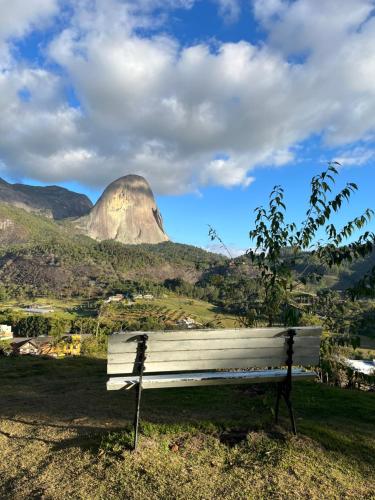 a bench in a field with a mountain in the background at Conecta Flats - De frente para Pedra Azul in Pedra Azul