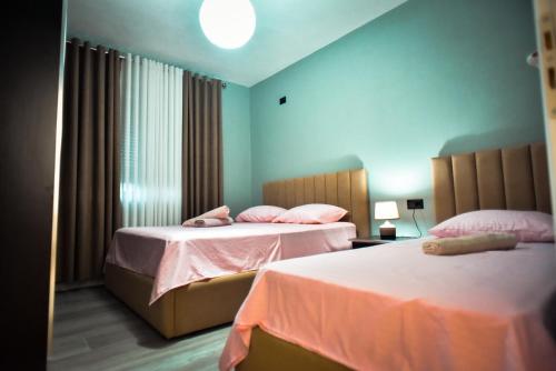 een slaapkamer met 2 bedden en roze lakens bij Temali Apartment in Shkodër