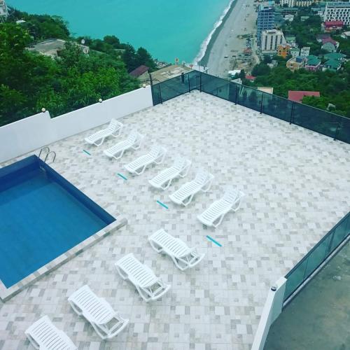 a group of lawn chairs and a swimming pool at Goga Guest House in Kvariati