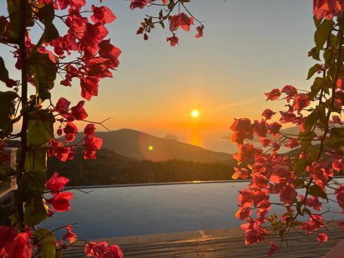 a sunset over a body of water with red flowers at Villa Ilda - Deluxe Holiday Villa - KALKAN-ANTALYA in Kalkan