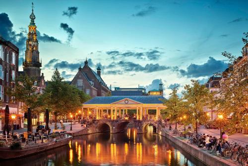 a building with a bridge over a river in a city at Leiden City Centre Canal View or Terrace View Apartments in Leiden