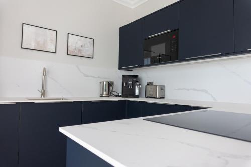 a kitchen with black cabinets and white counter tops at Oban Apartments in Oban