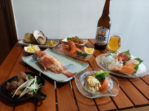 a table with plates of food and a bottle of beer at Abashirikai no Taiyo - Vacation STAY 14415 in Abashiri