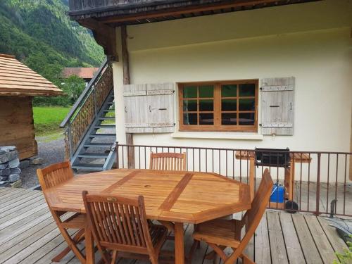 une table et des chaises en bois sur une terrasse dans l'établissement Appartement cosy aux Aravis (Clusaz/Grand-Bornand), à Entremont