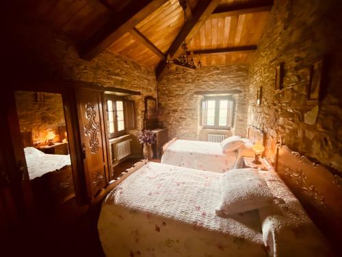a bedroom with two beds in a stone building at Casa da Costa de Sueiro in Sueiro