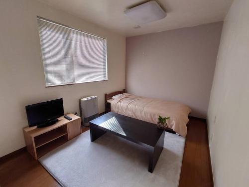 um pequeno quarto com uma cama e uma televisão em Abashirikai no Taiyo - Vacation STAY 14639 em Abashiri