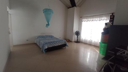 a bedroom with a bed and a window with a fan at Fresca casa de descanso en La Jagua in Garzón