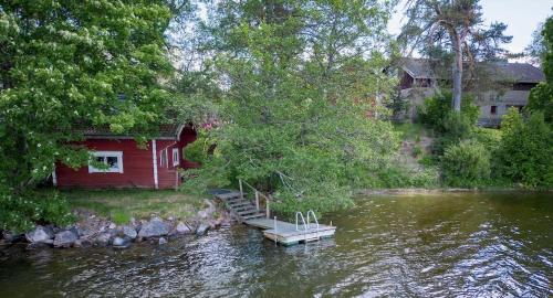une maison rouge au bord d'une rivière dans l'établissement Källgård, à Lohja