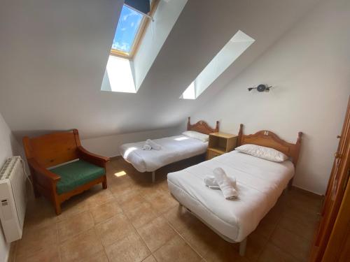 a attic room with two beds and a chair at Escuacho in Escarrilla