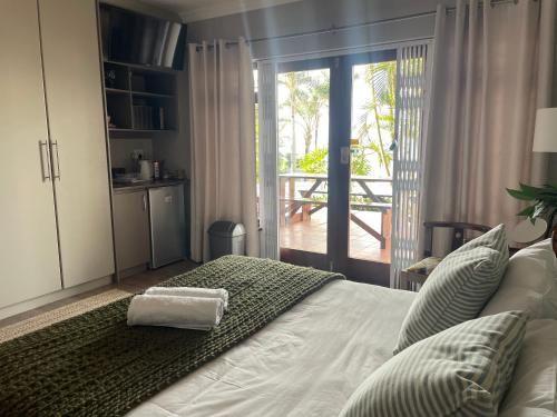 - une chambre avec un lit et une porte donnant sur une terrasse dans l'établissement Lazydaze Super and Tubes, à Jeffreys Bay