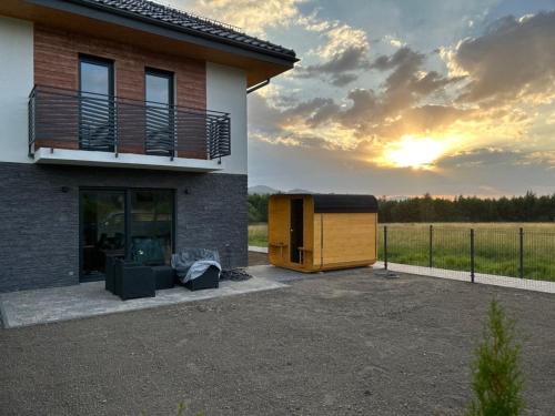 a house with a building with the sunset in the background at Apartament u Heleny in Sosnówka