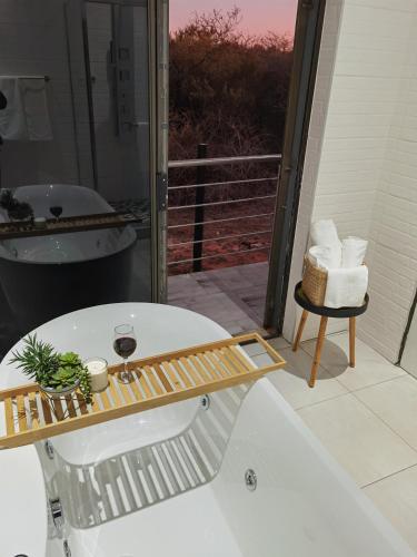 a bathroom with a bath tub and a glass of wine at Kings View Exclusive Villas (KVEV) in Petronella