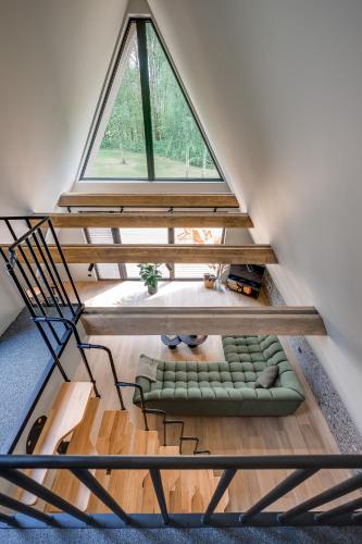 a loft with a window and a couch in a room at Namas MIŠKE in Lazdinė