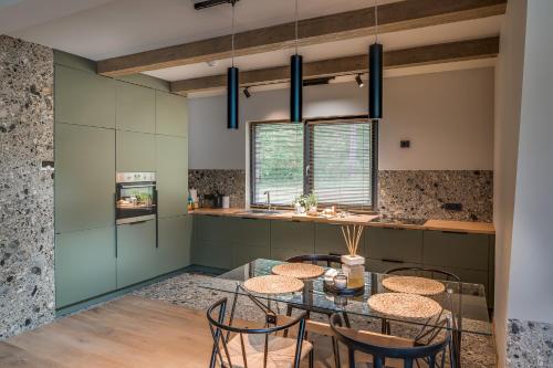 a kitchen with a glass table and chairs at Namas MIŠKE in Lazdinė