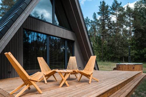 3 Stühle und ein Tisch auf einer Holzterrasse in der Unterkunft Namas MIŠKE 