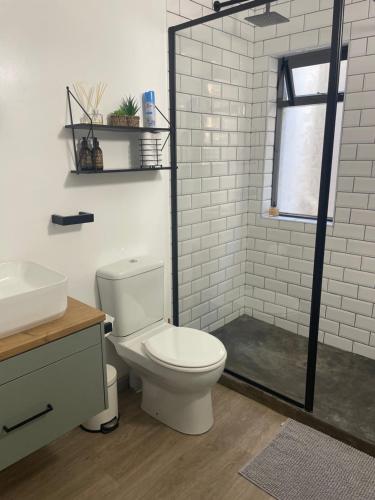 a white bathroom with a toilet and a shower at Lazydaze Super and Tubes in Jeffreys Bay