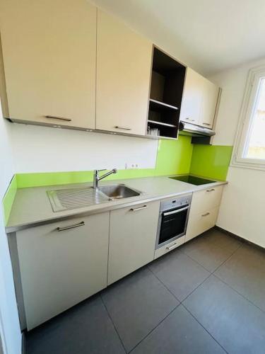 une cuisine avec des armoires blanches et un évier dans l'établissement Logement à 10 minutes à pied de la gare centre, à Avignon