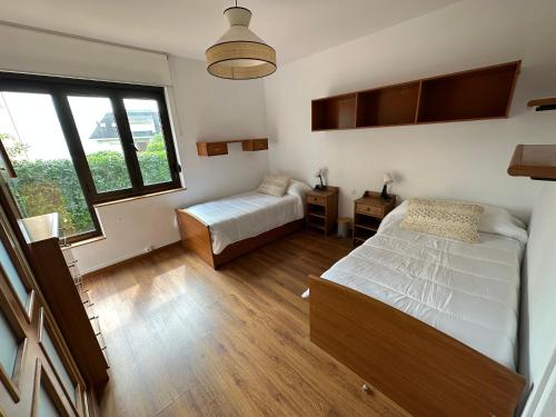 ein Schlafzimmer mit zwei Betten und einem Fenster in der Unterkunft CHALET ENTRE DOS PLAYAS TAPIA in Tapia de Casariego