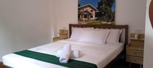 a bedroom with a bed with two towels on it at CASA MIA INN in Dauis