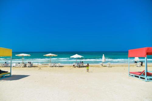 una playa con sombrillas y gente en la playa en شقة مفروشة 5 سراير في كامب شيزار, 