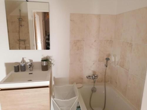 een badkamer met een bad, een wastafel en een spiegel bij LA MAISON BLEUE in Quiberon