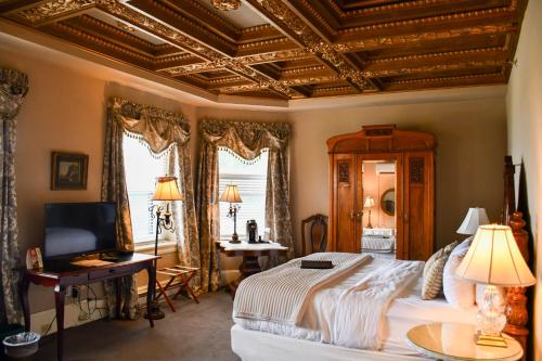 una camera con un grande letto e un soffitto a cassettoni di The Sayre Mansion a Bethlehem