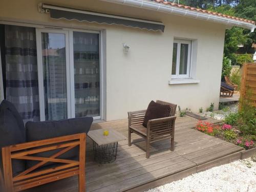 a wooden deck with two chairs and a table at Florecita petite maison in Labenne