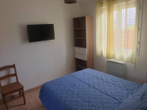 une chambre avec un lit, une télévision et une chaise dans l'établissement Florecita petite maison, à Labenne