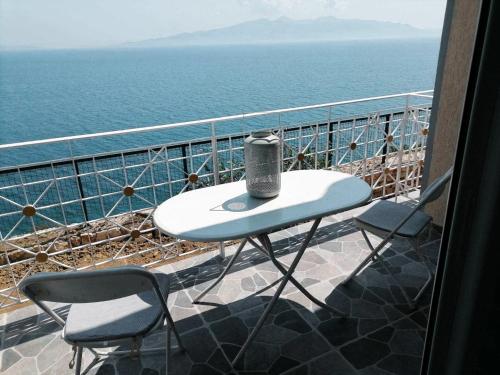 a table and two chairs on a balcony overlooking the ocean at Vila SHAKAJ in Sarandë