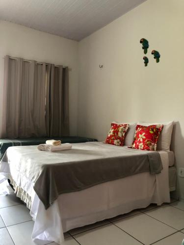 a bedroom with a large white bed with red pillows at Pousada Chácara do Coqueiro in Barreirinhas