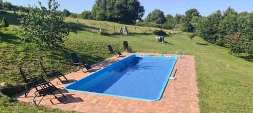 a swimming pool in a field with two chairs at Caserio de Fontes in Nogueira de Ramuin