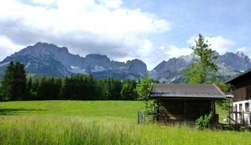 an old barn in a field with mountains in the background at Pension Sunnbichl in Going