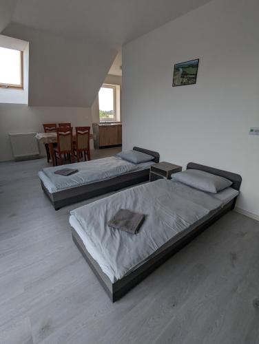 three beds in a room with a table and chairs at N&H Pansion in Mostová